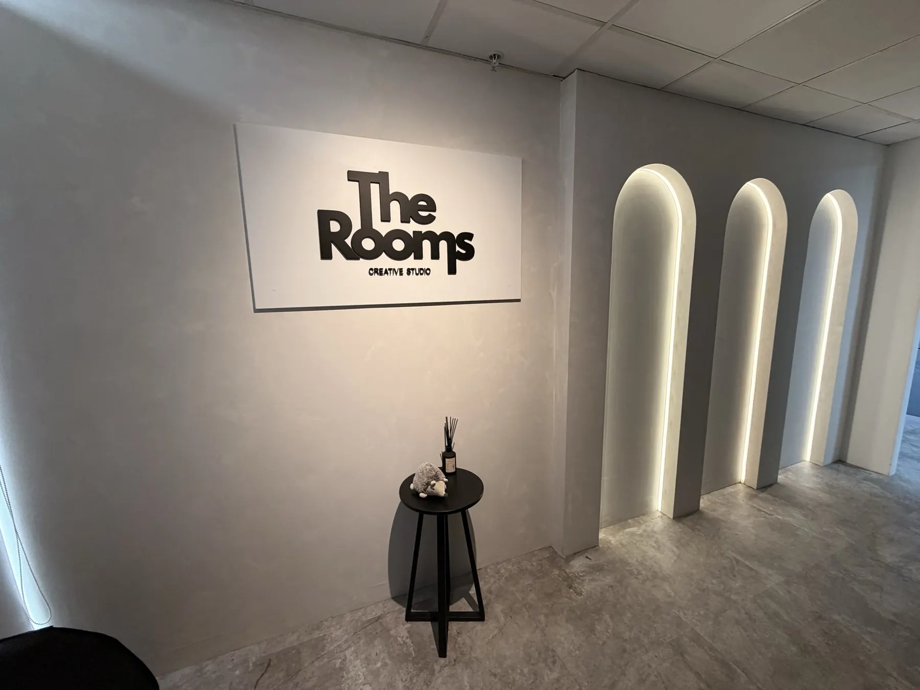 Recepción con el logo de The Rooms y arcos iluminados